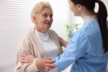 Obraz premium Nurse assisting senior woman indoors. Home health care service