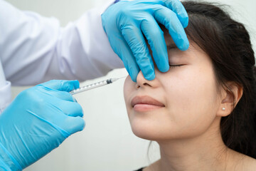 Asian woman receiving plastic surgery shape of nose performed on face.