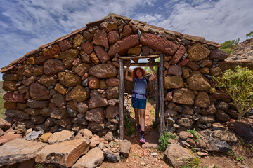 Hiker showing stone shelter in Teno