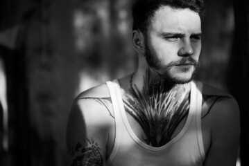 A striking black and white portrait of a man with a distinctive neck tattoo.