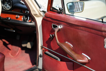The inner door handles of a vintage car are captured in a clean view, reflecting the classic design and preserved components that represent the simplicity and authenticity of vintage cars.