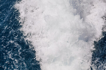 Close-up of foamy sea water churned by a boat. Abstract natural texture with movement, energy and clean copy space.