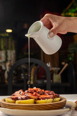 Chef pouring olive oil over pulpo a la gallega, octopus with potatoes