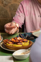 Customer eating grilled octopus with potatoes and mayonnaise sauce in restaurant