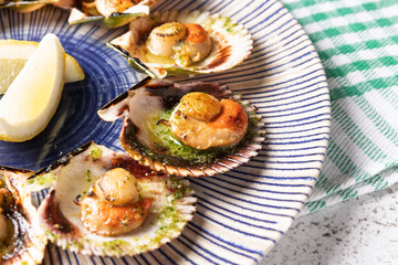 Grilled scallops with lemon and herbs on a decorative plate