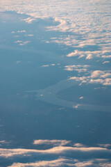 Aerial view of the winding Missouri River running through South Dakota, USA, seen through scattered clouds at high altitude during a flight