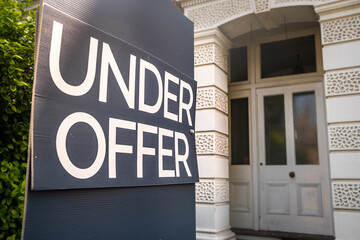 Estate agent 'Under Offer' sign on street of suburban British houses