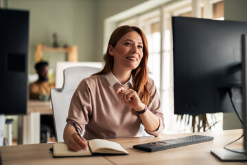 Professional Worker Smiling While Writing Notes in a Modern Office Environment
