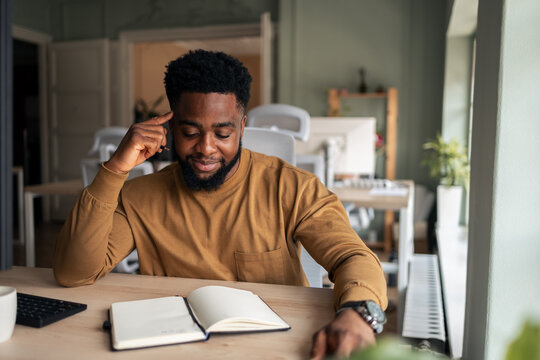 Man in a Modern Workspace Writing Notes in an Open Journal