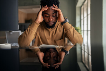Thoughtful Man Reflecting While Reading in Modern Workspace