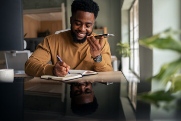 Smiling Man Working Remotely Talking on Phone and Writing Notes
