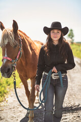 woman cowgirl, stands next to her horse in summer season
