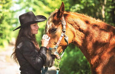 woman cowgirl, stands next to her horse in summer season