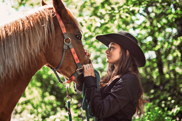 woman cowgirl, stands next to her horse in summer season