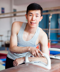 Portrait of asian gymnast in gym near pommel horse