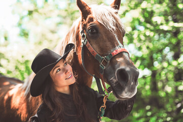 woman cowgirl, stands next to her horse in summer season