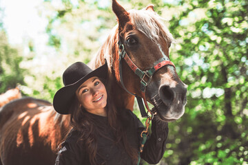 woman cowgirl, stands next to her horse in summer season