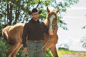cowboy, stands next to her horse in summer season
