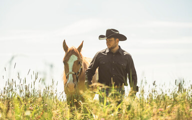cowboy, stands next to her horse in summer season