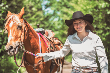 woman cowgirl, stands next to her horse in summer season