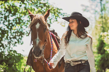 woman cowgirl, stands next to her horse in summer season