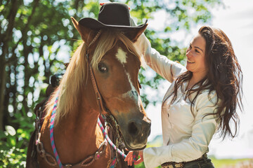 woman cowgirl, stands next to her horse in summer season