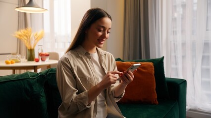 Caucasian woman girl female lady using mobile phone apps modern technology website at couch at home...