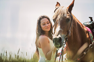 woman cowgirl, stands next to her horse in summer season