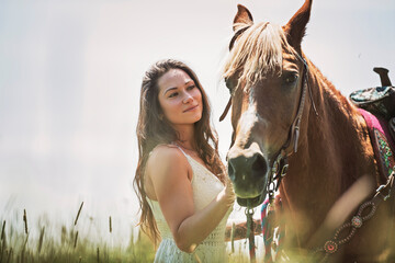 woman cowgirl, stands next to her horse in summer season