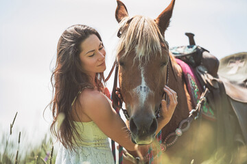 woman cowgirl, stands next to her horse in summer season
