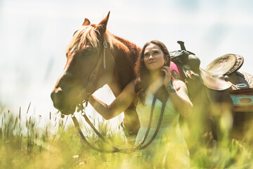 woman cowgirl, stands next to her horse in summer season
