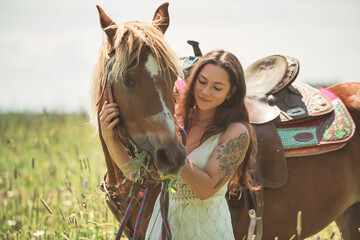 woman cowgirl, stands next to her horse in summer season