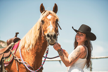 woman cowgirl, stands next to her horse in summer season