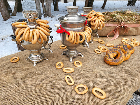 During the celebration of Maslenitsa. There are poppy seed rogues on a table covered with burlap. And there are three samovars