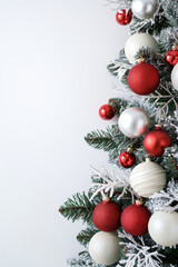 Red and white Christmas ornaments on frosted pine tree. Minimal holiday background.  
