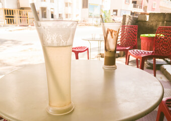 Two iced drinks on a cafe table outdoors in Bengaluru, India.  Shallow depth of field, sunlit...