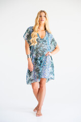 Fashionable blonde model in sheer beach pareo dress with leaf pattern, posing in studio for summer editorial shoot