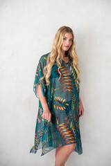 Naklejka premium Young blonde female wearing boho-inspired pareo dress with exotic patterns, minimal background fashion photo