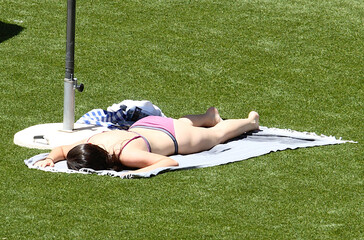 Mujer en bañador tipo bikini tumbada en la toalla tomando el sol poniéndose morena en verano...