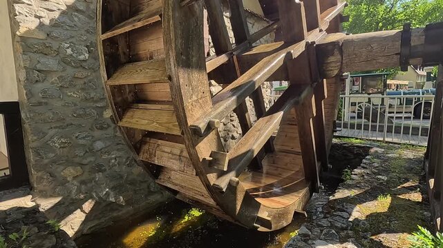 a close up shot of a large brown wooden water wheel with visible paddles and timber framework outdoors in a rural setting concept of history