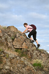 female tourist walking with backpack on beach and rocks
