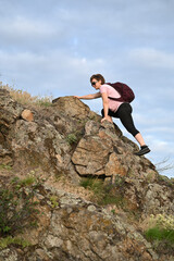 female tourist walking with backpack on beach and rocks