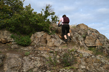 female tourist walking with backpack on beach and rocks