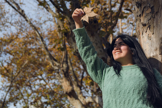 Young Venezuelan woman holds a leaf high with her hand blocking the sun