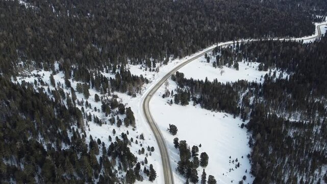 Aerial footage of a winding snow-covered road leading to Ust-Koksa in the Altai Republic, Russia. The video shows scenic winter landscapes with forests, hill