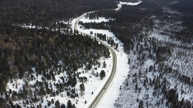 Aerial footage of a winding snow-covered road leading to Ust-Koksa in the Altai Republic, Russia. The video shows scenic winter landscapes with forests, hill