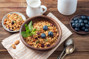 Oat granola with nuts, seeds and dry cranberries in wooden bowl. Healthy food concept