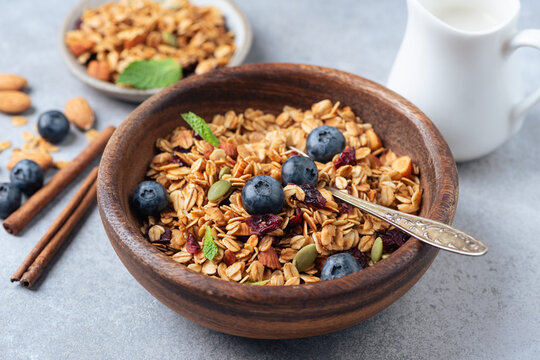 Crunchy homemade granola with almonds, blueberries in a wooden bowl, closeup view