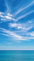 Obraz premium A serene ocean view under a vibrant blue sky with streaks of wispy white clouds.
