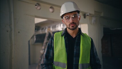 Serious Caucasian guy mechanic man repairman employee putting on safety glasses in construction...